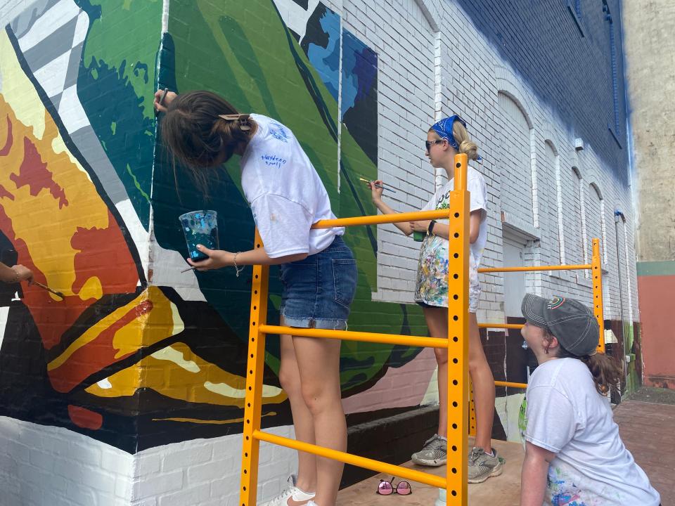 Lyla Cantu, 13, (left) and Gloria Harris, 14, (center) touch up the edges of a mural panel Thursday while spotter Willow Tucker, 15, (right) keeps watch.