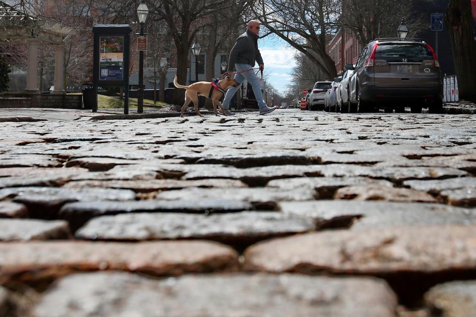 A man and his dog cross the cobbled section of Acushnet Avenue in downtown New Bedford. This weekend, filmmakers will be downtown working on short film projects.