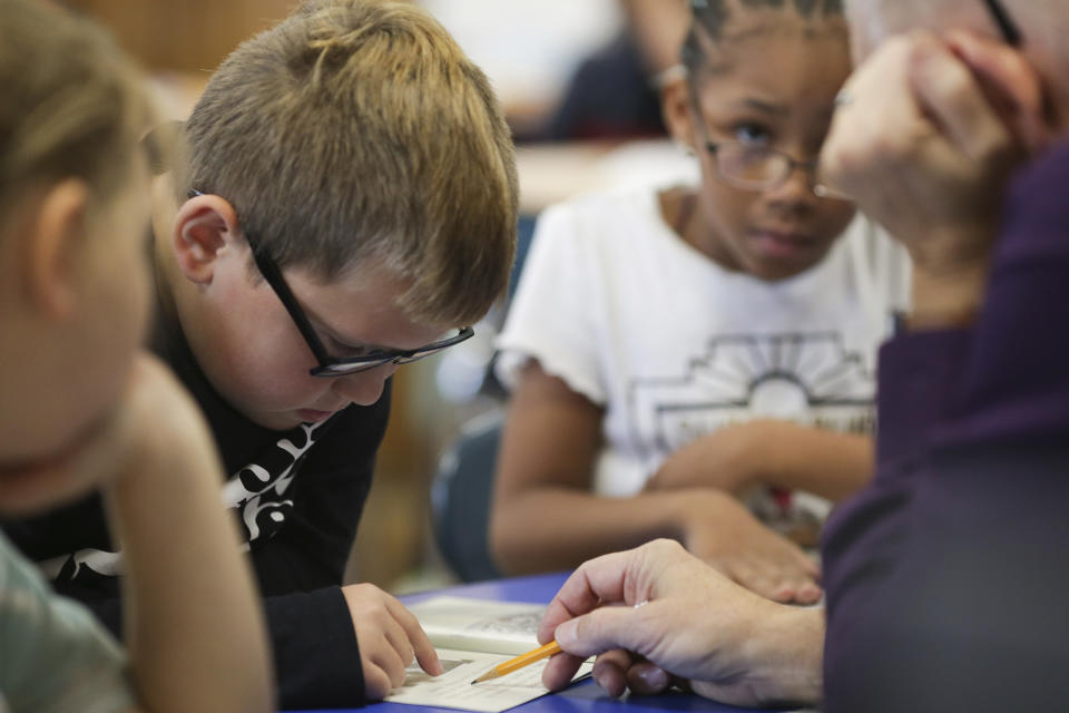 Dylan Mayes, left, reads from a book about Willie Mays during a reading circle in class on Thursday, Oct. 20, 2022, in Niagara Falls, N.Y. In a year that is a high-stakes experiment on making up for missed learning, a strategy of assessing individual students’ knowledge and tailoring instruction to them is among the most widely adopted in American elementary schools. (AP Photo/Joshua Bessex)