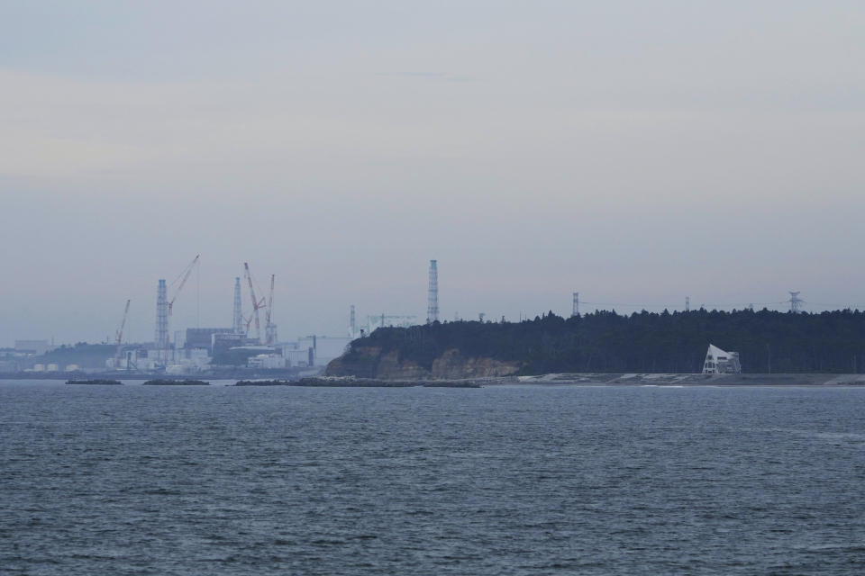 The Fukushima Daiichi nuclear power plant, damaged by a massive March 11, 2011, earthquake and tsunami, is seen from the nearby Ukedo fishing port in Namie town, northeastern Japan, Friday, July 14, 2023. A beach house damaged by the 2011 disaster is seen at right. (AP Photo/Hiro Komae)