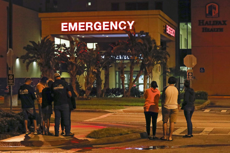 Race fans wait outside the emergency room of Halifax Health Medical Center where Ryan Newman was taken after he was involved in a crash during the final lap of the NASCAR Daytona 500 auto race at Daytona International Speedway, Monday, Feb. 17, 2020, in Daytona Beach, Fla. (AP Photo/Terry Renna)