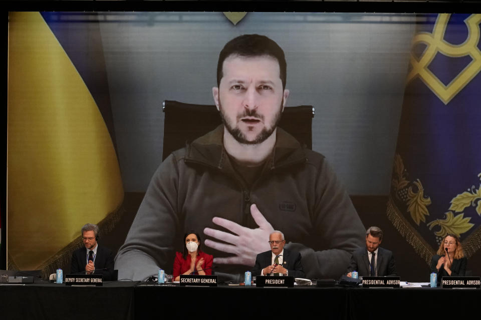 Ukrainian President Volodymyr Zelenskyy appears on a large screen as he speaks via video conference during the 68th Annual Session of the NATO Parliamentary Assembly in Madrid, Spain, Monday, Nov. 21, 2022. (AP Photo/Andrea Comas)