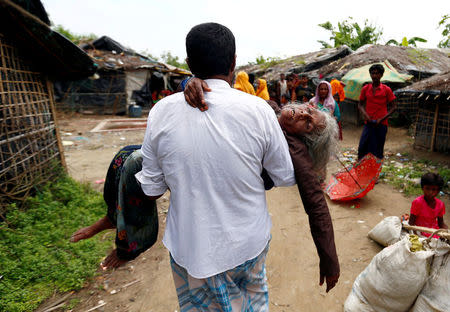 A man carries a Rohingya refugee woman from the shore after she crossed the Bangladesh-Myanmar border by boat through the Bay of Bengal in Teknaf, Bangladesh September 7, 2017. REUTERS/Danish Siddiqui