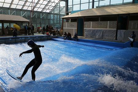 Lauren McLean tests the waves on a surfboard at the still under-construction Surf's Up indoor water and surf park in Nashua, New Hampshire November 15, 2013. REUTERS/Brian Snyder