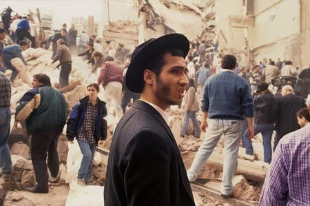 FILE PHOTO: People look on after an explosives-laden truck blew up outside the Argentine Israeli Mutual Association (AMIA) building on July 18 1994, in Buenos Aires