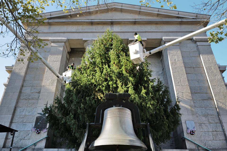 Carlos Medina and Jason Perry of New Bedford DPI install the lights on the Christmas Tree installed in front of the public library in downtown New Bedford.