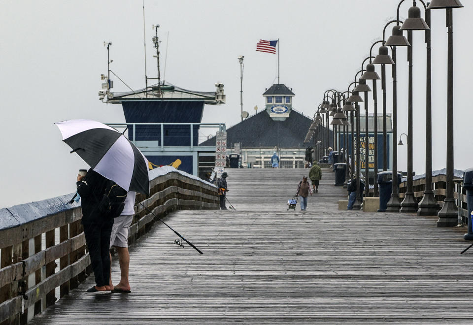 Imperial Beach, CA - September 09: Despite high wind and rain, people enjoy the stormy weather during the morning hours on the Imperial Beach Pier on Friday, Sept. 9, 2022 in Imperial Beach, Calif. A surge of clouds and showers associated with Tropical Storm Kay off Mexico's Baja California peninsula knocked the edge off temperatures in Southern California at times but also were a potential problem for solar generation. The storm was downgraded from a hurricane Thursday evening. (Eduardo Contreras/The San Diego Union-Tribune via AP)