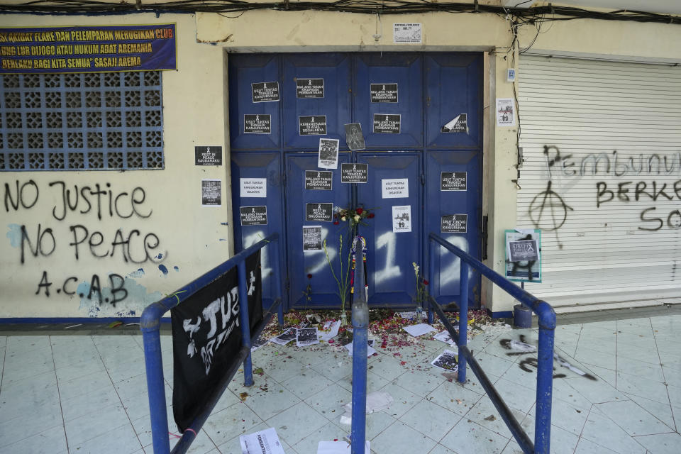 Protest signs cover a gate at the Kanjuruhan Stadium in Malang, Indonesia, Tuesday, Oct. 4, 2022. Police said Tuesday that the gates at the soccer stadium where police fired tear gas and set off a deadly crush were too small and could only accommodate two at a time when hundreds were trying to escape. (AP Photo/Achmad Ibrahim)