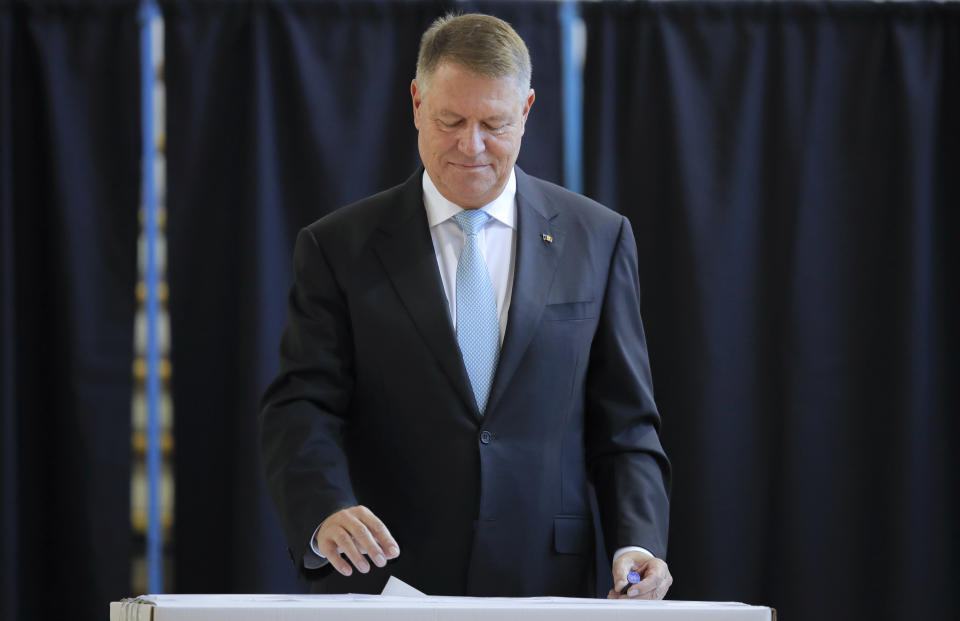 Romanian President Klaus Iohannis casts his vote in Bucharest, Romania, Sunday, Nov. 10, 2019. Voting got underway in Romania's presidential election after a lackluster campaign overshadowed by a political crisis which saw a minority government installed just a few days ago. (AP Photo/Vadim Ghirda)