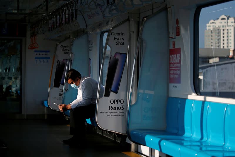 FILE PHOTO: A man wearing face mask sits inside a Mass Rapid Transit train in Jakarta