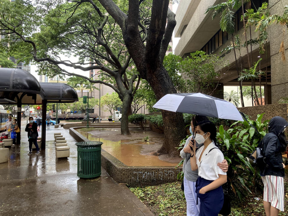 People in downtown Honolulu contend with heavy rain and flooding, Monday, Dec. 6, 2021. A strong storm packing high winds and extremely heavy rain has flooded roads and downed power lines and tree branches across Hawaii. (AP Photo/Jennifer Sinco Kelleher)