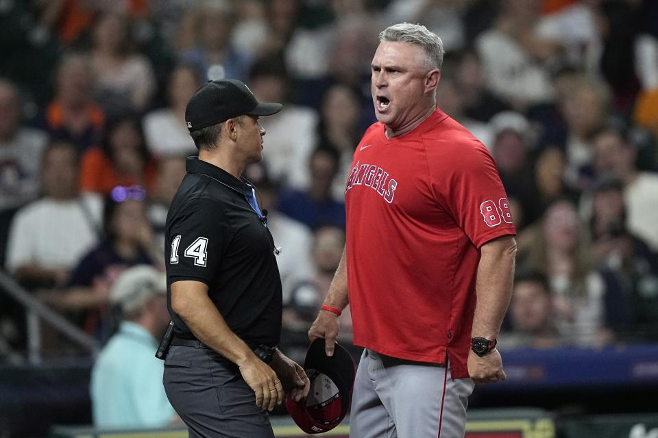 Los Angeles Angels manager Phil Nevin (88) yells at home plate umpire Stu Scheurwater as second base umpire Mark Wegner (14) stands between them during the sixth inning of a baseball game against the Houston Astros Thursday, June 1, 2023, in Houston. Nevin was ejected after arguing a strike-three call. (AP Photo/David J. Phillip)