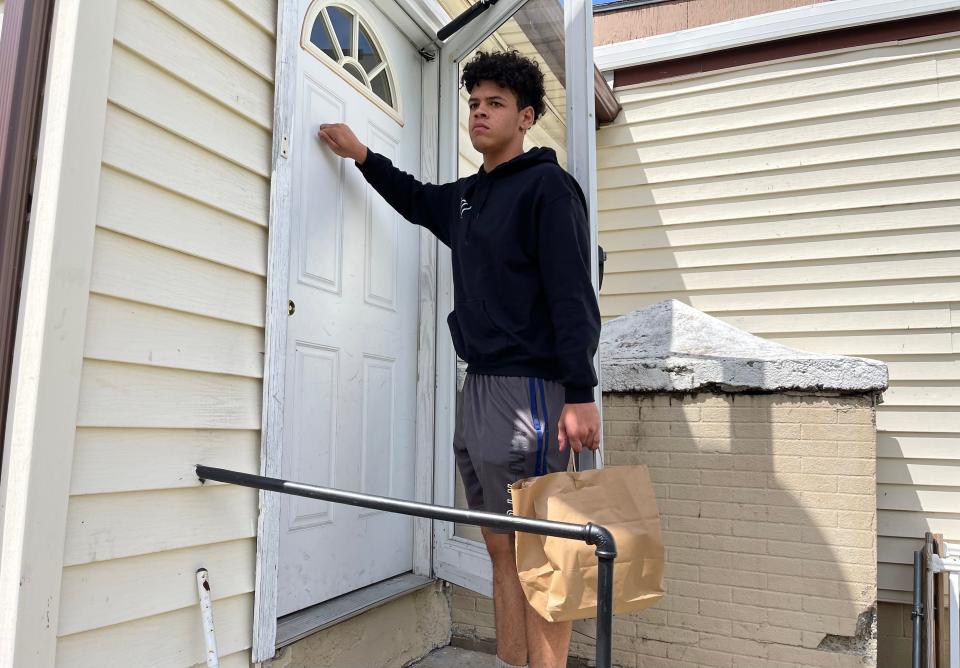 Max-Yamil Cabezudo-Brown knocks on a door to deliver groceries for PLP Rochester's Free Grocery Program.