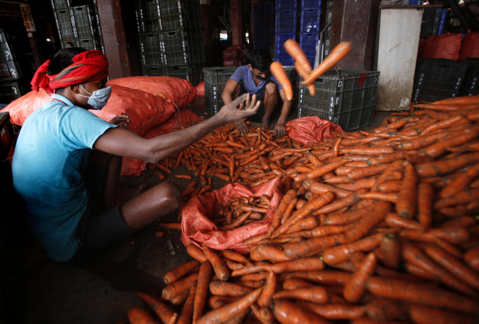 A worker wearing a face mask as a precaution against the coronavirus sorts carrots at a wholesale market Mumbai, India, Tuesday, June 15, 2021. (AP Photo/Rafiq Maqbool)