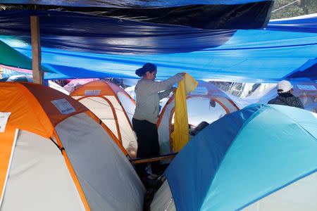 A resident folds a rain jacket in a provincial campsite after her house was affected by the the earthquake in Mexico City, Mexico September 25, 2017. REUTERS/Carlos Jasso