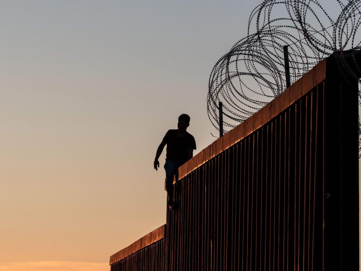 A man walks along the top of the fence separating the US and Mexico in California: AFP/Getty Images
