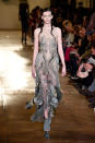 <p>Ein Model trägt bei der Iris Van Herpen Frühjahr/Sommer 18 Haute Couture Modenschau ein halbdurchsichtiges Kleid mit silbernen und goldenen Verzierungen. (Bild: Getty Images) </p>