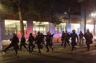 Portland police chase demonstrators during a Black Lives Matter protest Sunday, July 26, 2020, in Portland, Ore. (AP Photo/Marcio Jose Sanchez)