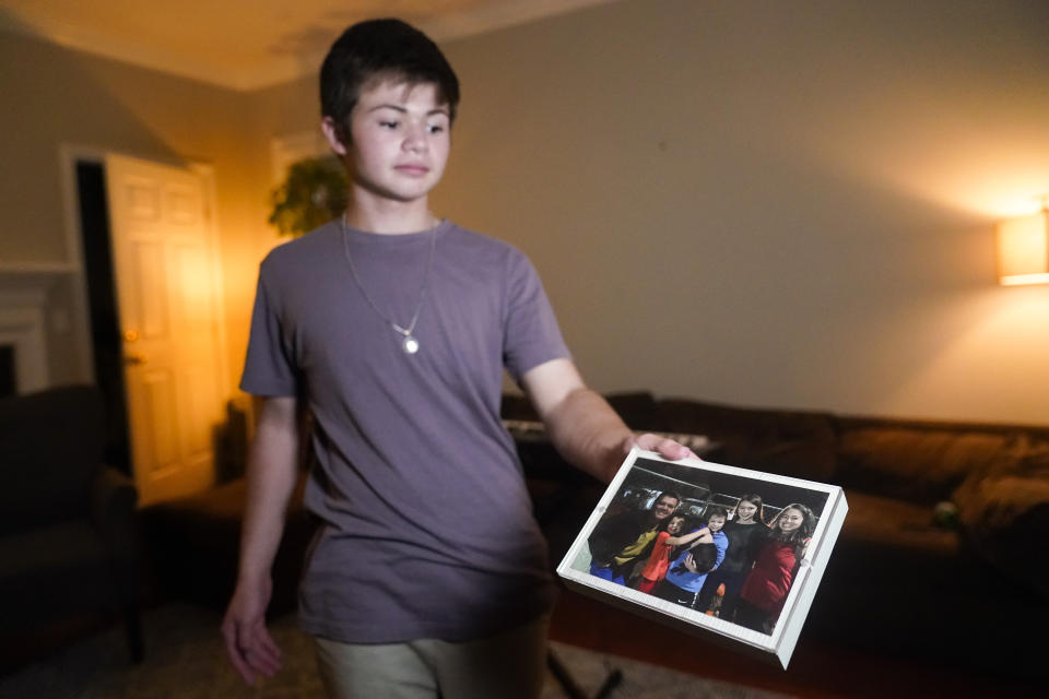 Callum Bradford shows a family picture at his home, Thursday, Sept. 14, 2023, in Chapel Hill, N.C. Bradford, a transgender teen from Chapel Hill needed mental health care after overdosing on prescription drugs. He was about to be transferred to another hospital due to a significant bed shortage. A North Carolina hospital network is referring transgender psychiatric patients to treatment facilities that do not align with their gender identities. Though UNC Hospitals policy discourages the practice, administrators say a massive bed shortage is forcing them to make tough decisions. (AP Photo/Erik Verduzco)