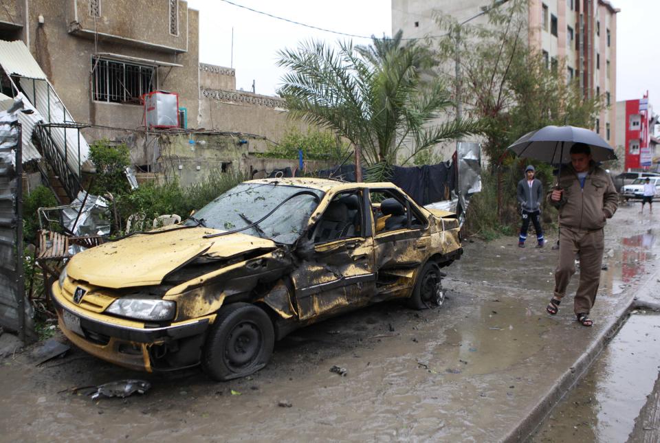 Iraqi civilians inspect the site of a car bomb in a commercial area in the Hurriyah neighborhood of northern Baghdad, Iraq, Monday, Feb. 3, 2014. Iraqi officials say car bombings on Monday in and near Baghdad have killed and wounded scores of people. (AP Photo/Hadi Mizban)