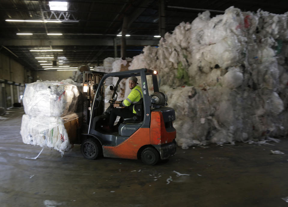 In this May 7, 2019 photo, a forklift moves through stacks of recyclables at a GDB International warehouse in Monmouth Junction, N.J. GDB International exported bales of scrap plastic film such as pallet wrap and grocery bags for years. But when China started restricting imports, company president Sunil Bagaria installed new machinery to process it into pellets he sells profitably to manufacturers of garbage bags and plastic pipe. (AP Photo/Seth Wenig)