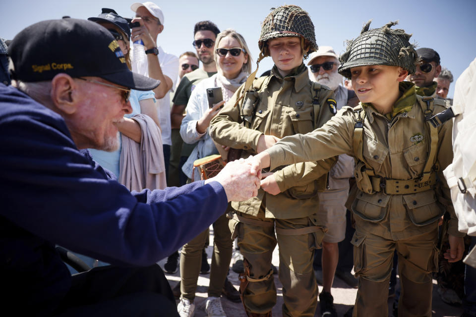 CORRECTS LOCATION A U.S. veteran shakes hands with a World War II enthusiasts during a gathering in preparation of the 79th D-Day anniversary in Sainte-Mere-Eglise, Normandy, France, Sunday, June 4, 2023. The landings on the coast of Normandy 79 year ago by U.S. and British troops took place on June 6, 1944. (AP Photo/Thomas Padilla)