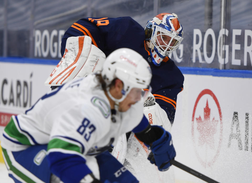 Edmonton Oilers goalie Mikko Koskinen (19) and Vancouver Canucks' Jay Beagle (83) work for the puck during the third period of an NHL hockey game Wednesday, Jan. 13, 2021, in Edmonton, Alberta. (Dale MacMillan/The Canadian Press via AP)