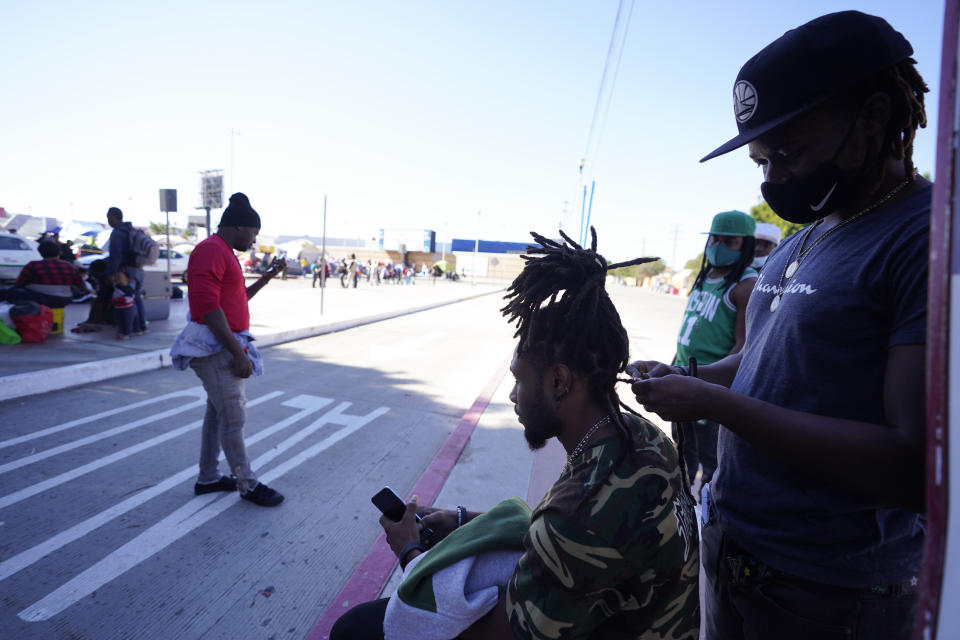 Jean Adler Cactus, right, a Haitian migrant seeking asylum in the United States, works on the hair of Haitian migrant Thomas Volcy, near an entrance to the border crossing, Monday, March 1, 2021, in Tijuana, Mexico. Though Haitians living in the U.S. rejoiced when a recent extension was granted, Homeland Security Secretary Alejandro Mayorkas pointedly noted that it doesn't apply to Haitians outside the U.S. and said those who enter the country may be flown home. That means bleak choices for many Haitians who fled Haiti sometime after a 2010 earthquake, initially escaping to South America and later to Mexican cities that border the United States. (AP Photo/Gregory Bull)