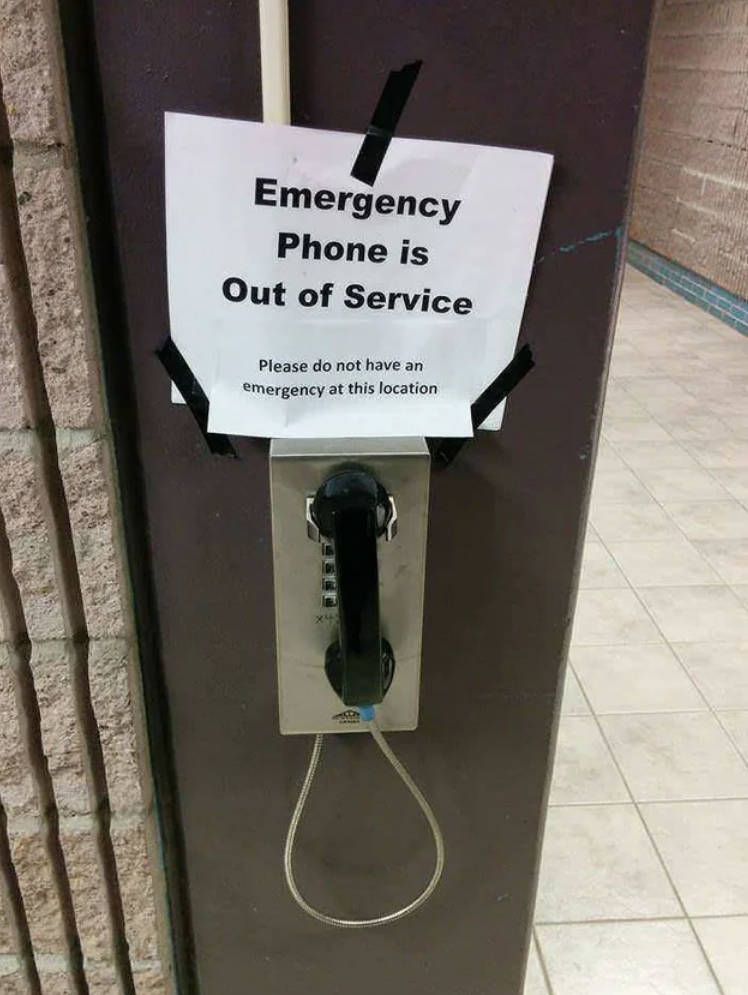 A sign above a public phone says "emergency phone out of service, please do not have an emergency at this location"