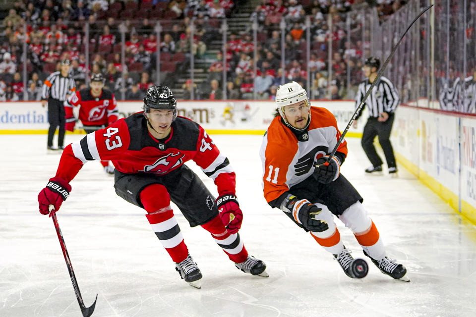 New Jersey Devils defenseman Luke Hughes (43) and Philadelphia Flyers right wing Travis Konecny (11) vie for the puck during the first period of an NHL hockey game in Newark, N.J., Tuesday, Dec. 19, 2023. (AP Photo/Peter K. Afriyie)