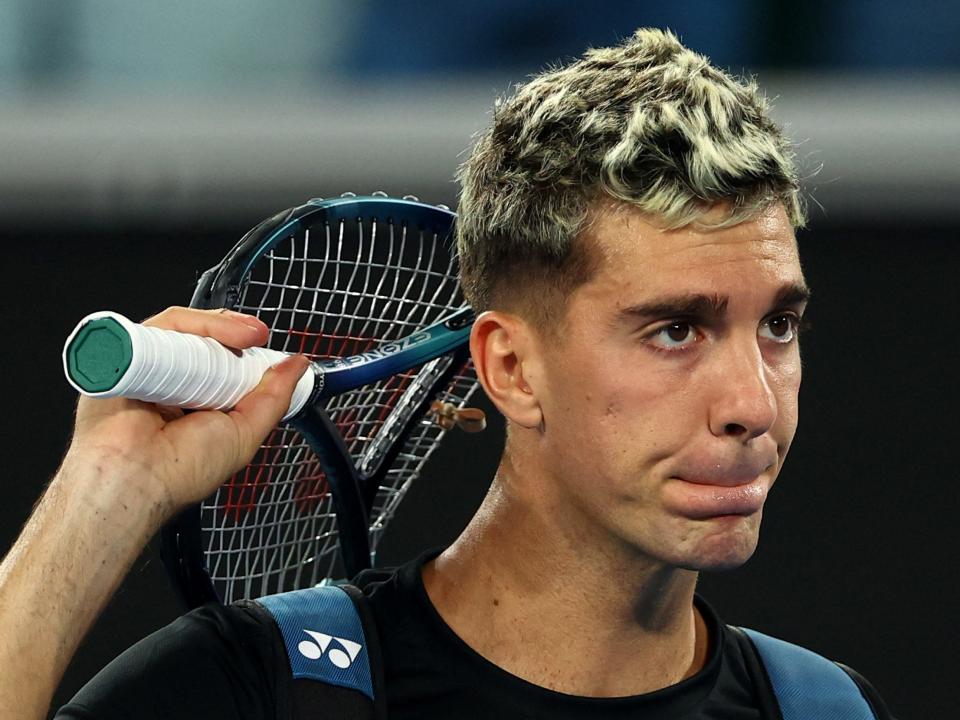 Thanasi Kokkinakis leaves the court with his mangled racket after losing his second-round Australian Open match.