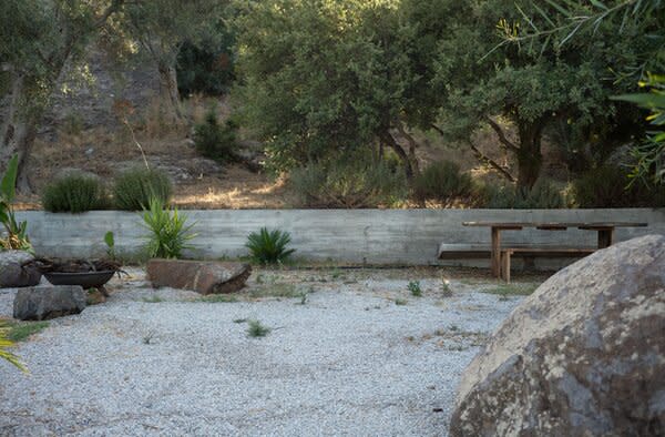 A retaining wall, seating, and natural rock formations create an intriguing garden vignette.