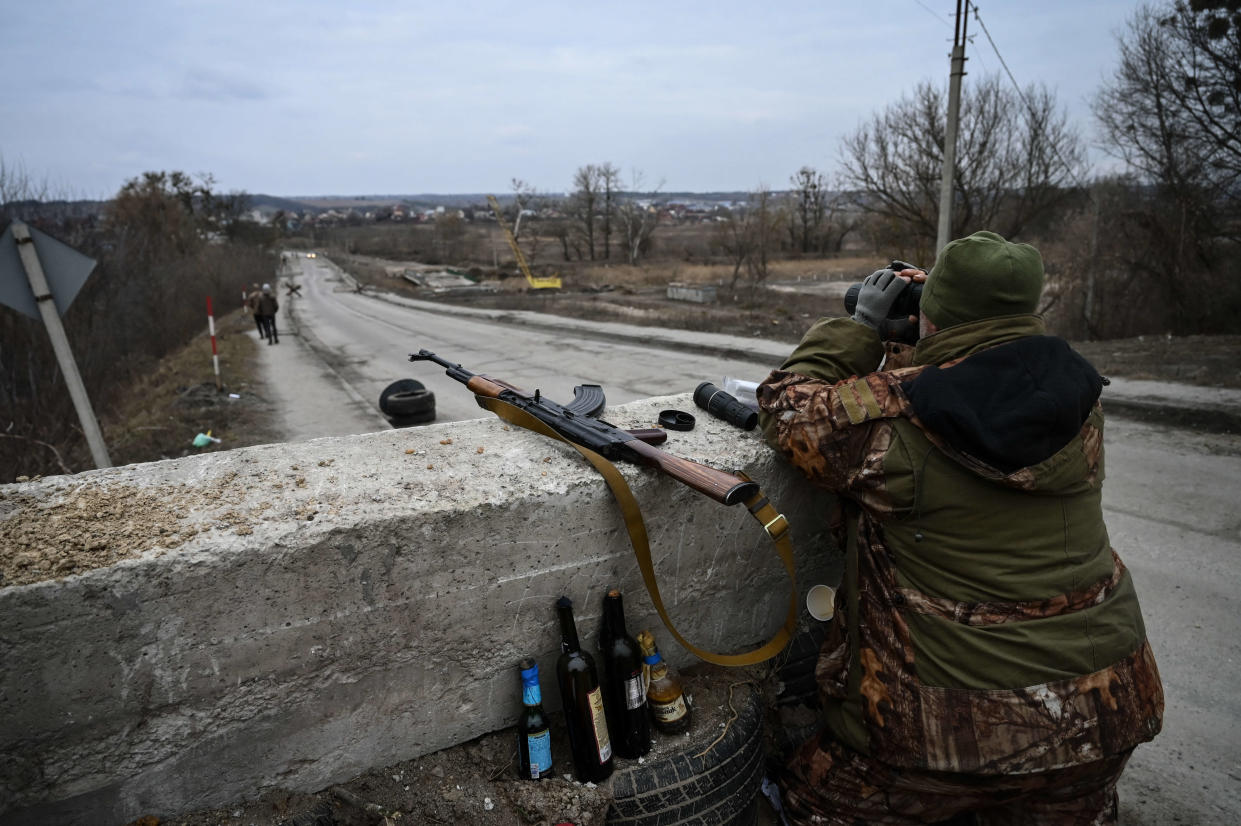 TOPSHOT - An Ukrainian serviceman looks through binoculars towards the town of Stoyanka at a checkpoint before the last bridge on the road that connects Stoyanka with Kyiv, on March 6, 2022. (Photo by ARIS MESSINIS / AFP)