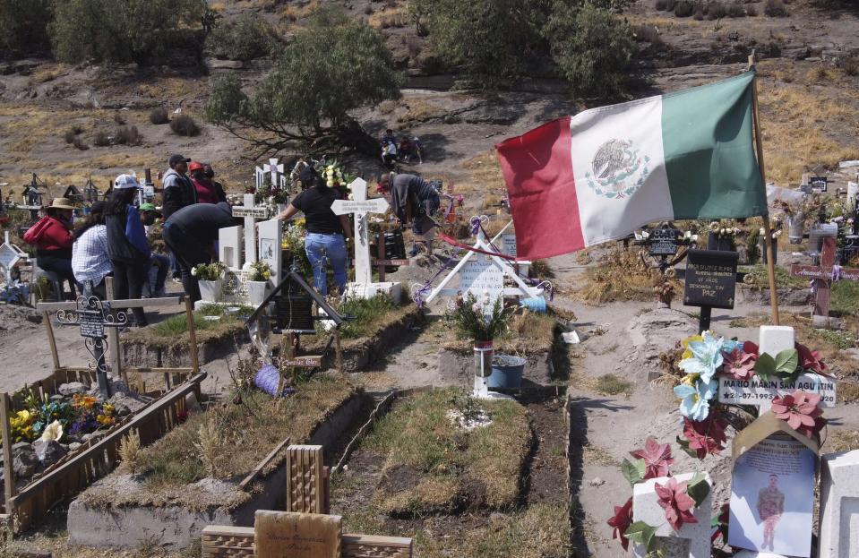 Family members attend the burial service of a relative who died of complication related to COVID-19, at the Valle de Chalco municipal cemetery on the outskirts of Mexico City, Saturday, Jan. 30, 2021. Due to the high number of recent deaths, many due to the new coronavirus pandemic, Mexico City's cemeteries are filled to capacity. (AP Photo/Christian Palma)