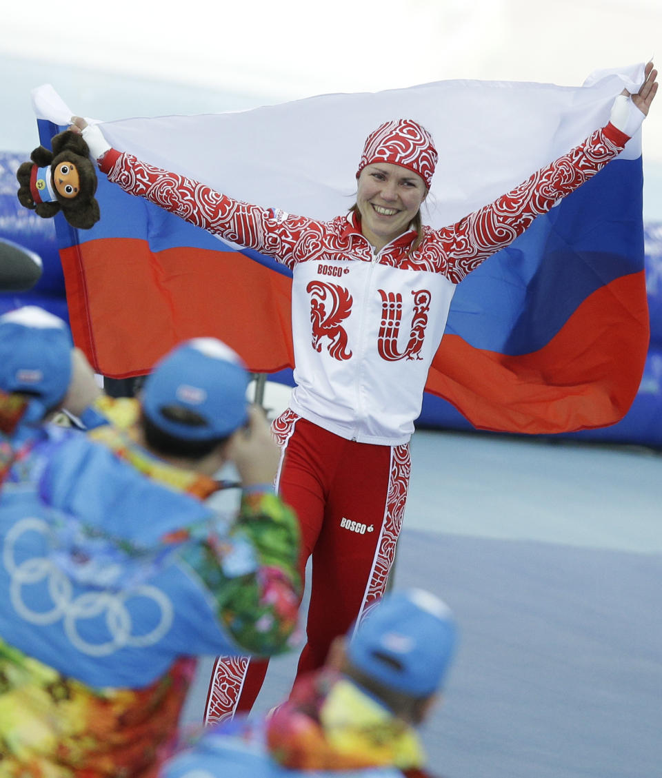 Russia's Olga Graf holds her national flag and celebrates winning bronze in the women's 3,000-meter speedskating race at the Adler Arena Skating Center during the 2014 Winter Olympics, Sunday, Feb. 9, 2014, in Sochi, Russia. (AP Photo/Pavel Golovkin)