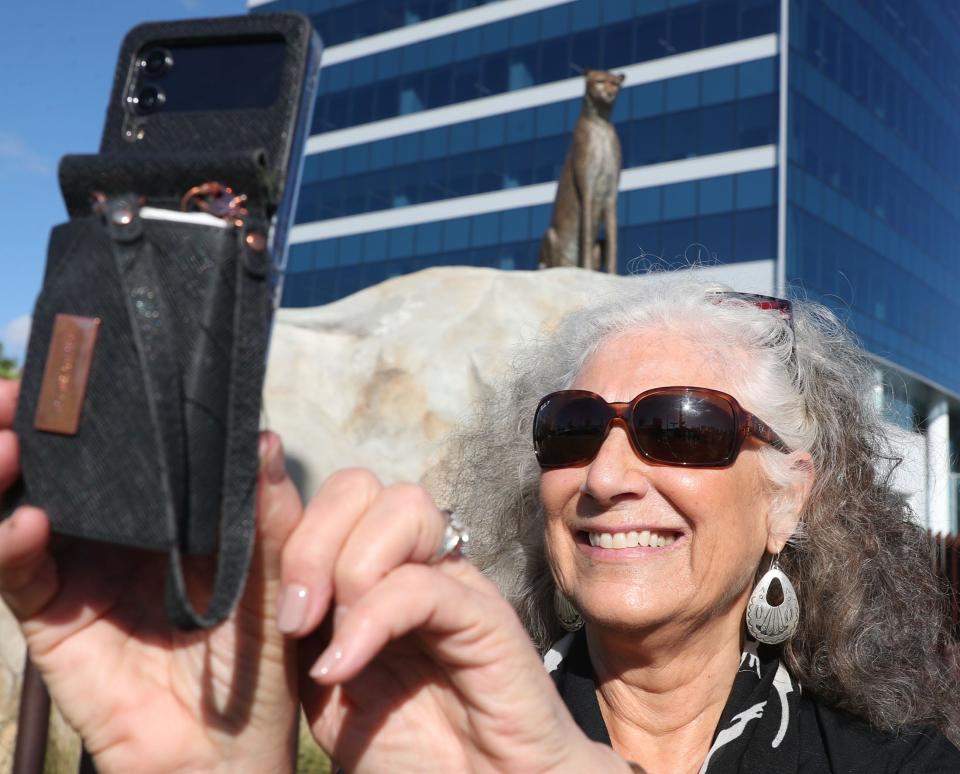 Dr. Laurie Marker, founder of the Namibia, Africa-based Cheetah Conservation Fund, takes a selfie in front of the bronze cheetah sculpture in front of the headquarters for Brown & Brown Insurance at 300 N. Beach St., Daytona Beach on Monday, Oct. 30, 2023. This is her first time seeing the statue created by Palm Coast sculptor Paul Baliker. Brown & Brown has been using the cheetah, the world's fastest land animal, as its symbol since the 1980s.