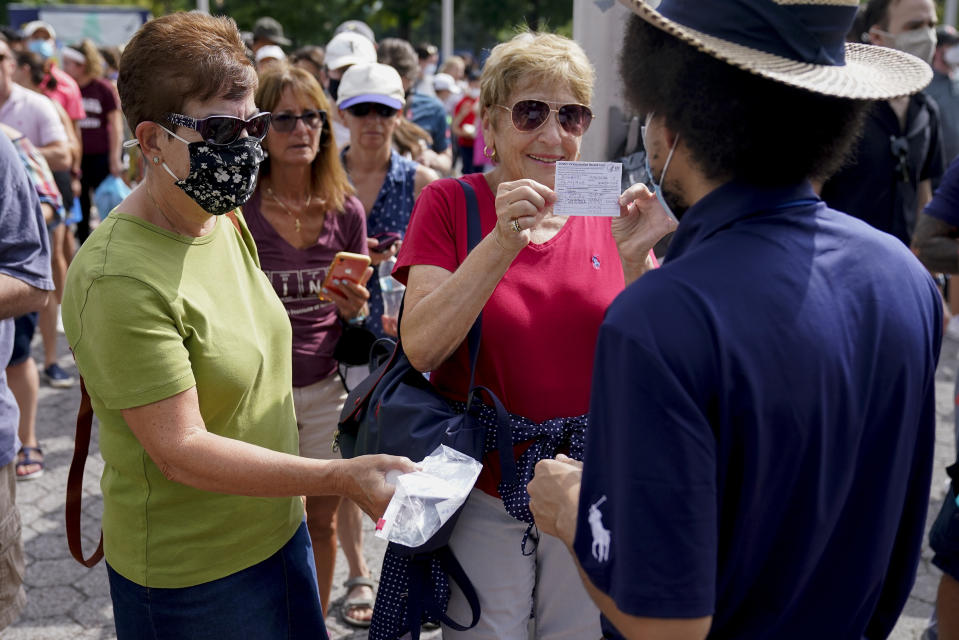 Espectadores muestran sus certificados de vacunación para poder acudir a la primera ronda del Abierto de Estados Unidos de tenis, el lunes 30 de agosto de 2021, en Nueva York. (AP Foto/Seth Wenig)