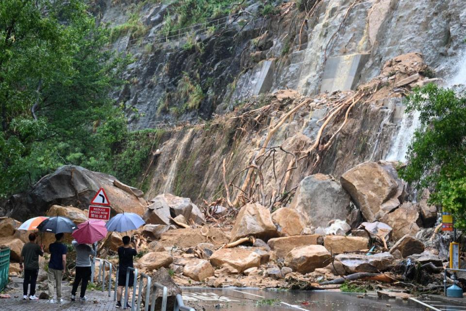 Plainclothes officials and police look at a landslide covering a road at Yiu Tung Estate in Shau Kei Wan in Hong Kong (AFP via Getty Images)