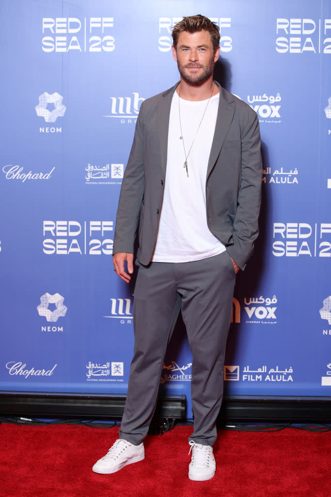 Chris Hemsworth in a semi-formal grey suit with white sneakers at a red carpet event