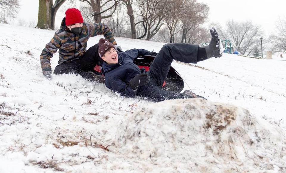 Declan Kearns, right, and Finn Langston fall off their sled while trying to hit a jump they made on Wednesday, Jan. 25, 2023, in Kansas City.