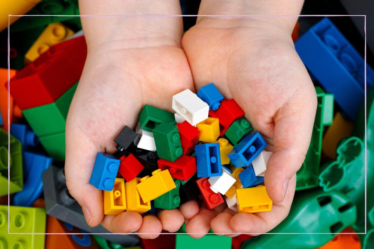  A close up of a person holding LEGO blocks in their hands. 