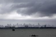 Fishermen ride on their boat as dark clouds loom over the city brought by Super Typhoon Usagi in Navotas City, metro Manila September 21, 2013. The year's most powerful typhoon slammed into the Philippines' northernmost islands on Saturday, cutting communication and power lines, triggering landslides and inundating rice fields, officials said. Packing winds of 185 kph (114 mph) near the center and gusts of up to 220 kph, Typhoon Usagi weakened after hitting the Batanes island group, and is moving slowly west-northwest at 19 kph towards southern China, the weather bureau said. REUTERS/Romeo Ranoco (PHILIPPINES - Tags: DISASTER SOCIETY ENVIRONMENT CITYSCAPE)