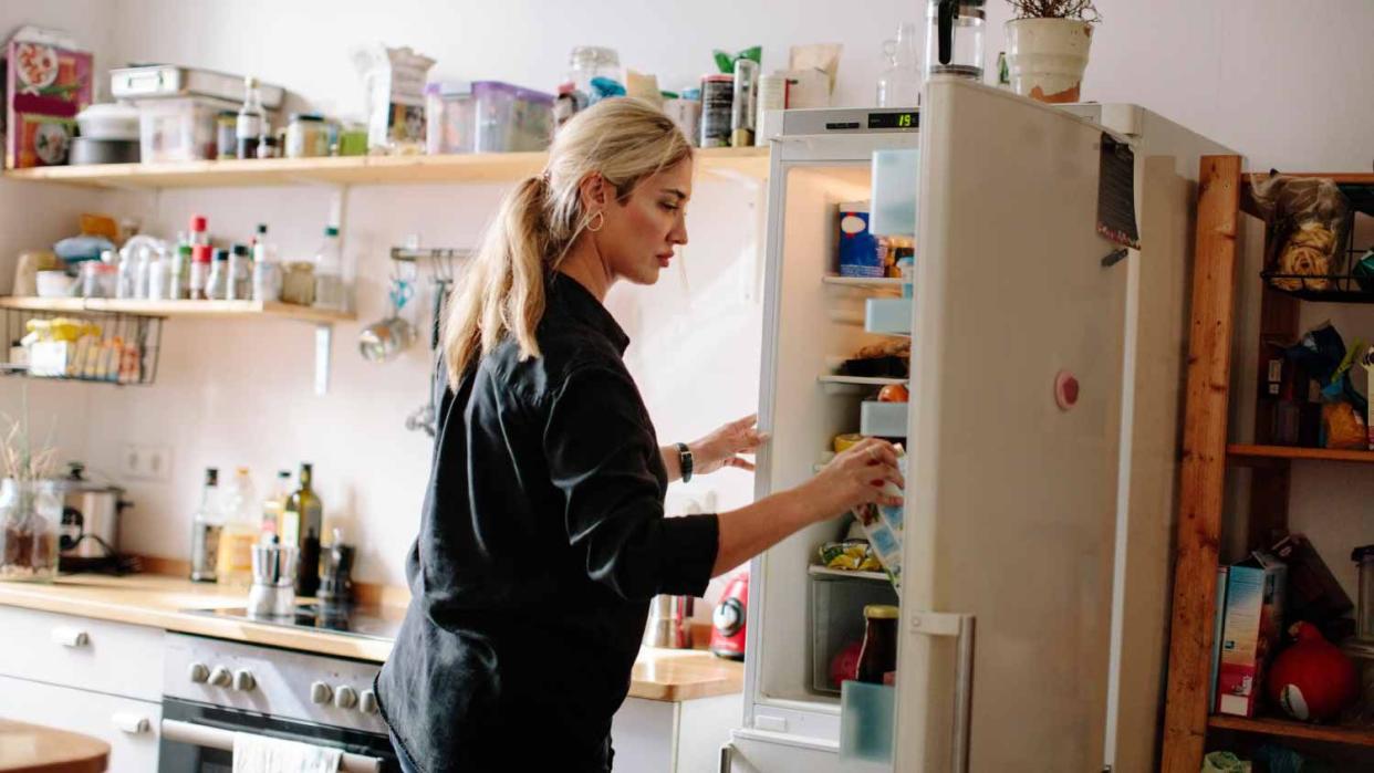 Woman opening refrigerator in kitchen