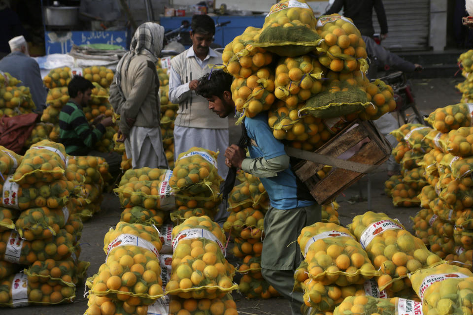 FILE - A laborer carries sacks of oranges in a wholesale fruit market in Lahore, Pakistan, on Dec. 1, 2021. Growing numbers of people in Asia lack enough food to eat as food insecurity rises with higher prices and worsening poverty, according to a report by the Food and Agricultural Organization and other UN agencies released Tuesday, Jan. 24, 2023. (AP Photo/K.M. Chaudary, File)