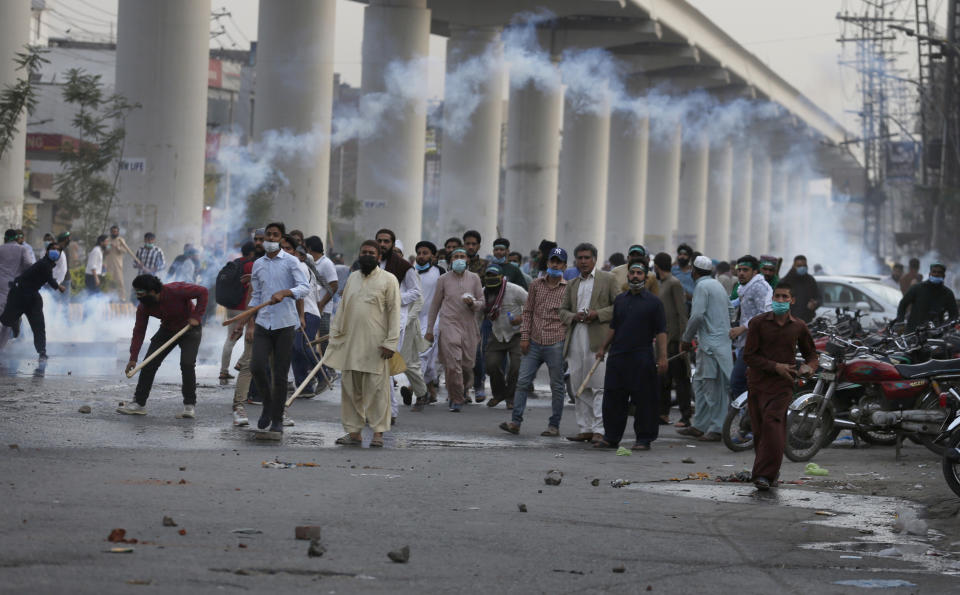 Angry supporters of Tehreek-e-Labiak Pakistan, a radical Islamist political party, throw stones towards police firing tear gas to disperse them, at a protest against the arrest of their leader Saad Rizvi, in Lahore, Pakistan, Monday, April 12, 2021. Pakistan police arrested Rizvi a day after he threatened the government with protests if it did not expel France's ambassador over depictions of Islam's Prophet Muhammad. (AP Photo/K.M. Chaudary)