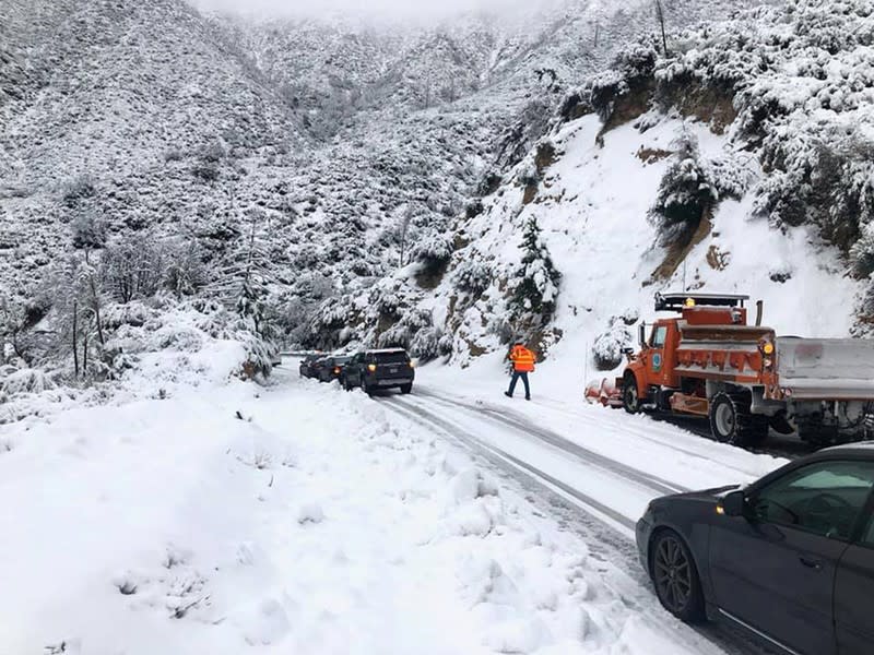 Cars stranded due to snowfall on the Angeles Crest Highway are assisted by a Caltrans crew in the Angeles National Forest