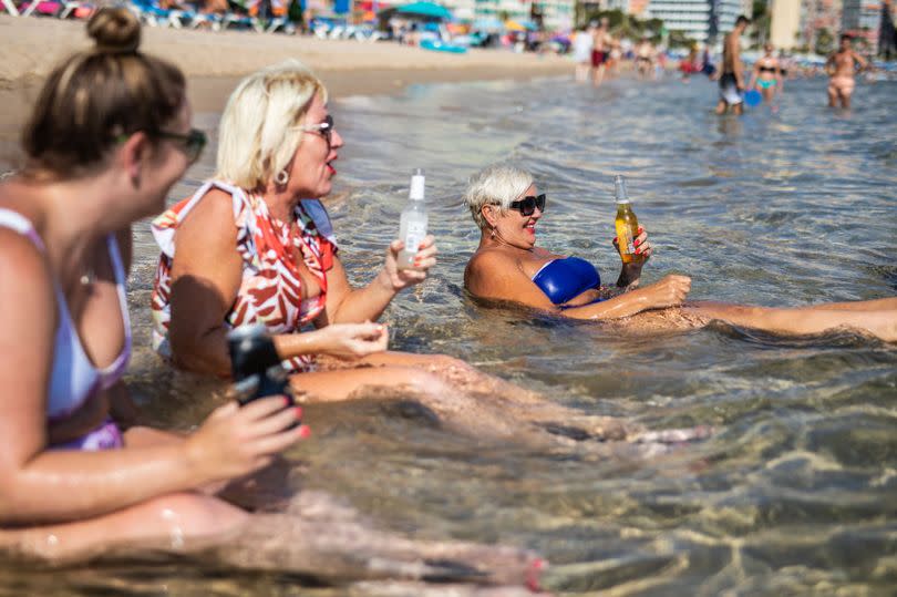 English tourists quench the heat by drinking in the sea at Levante beach, Benidorm