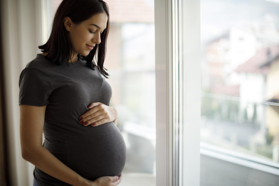 A pregnant woman glancing down at her belly