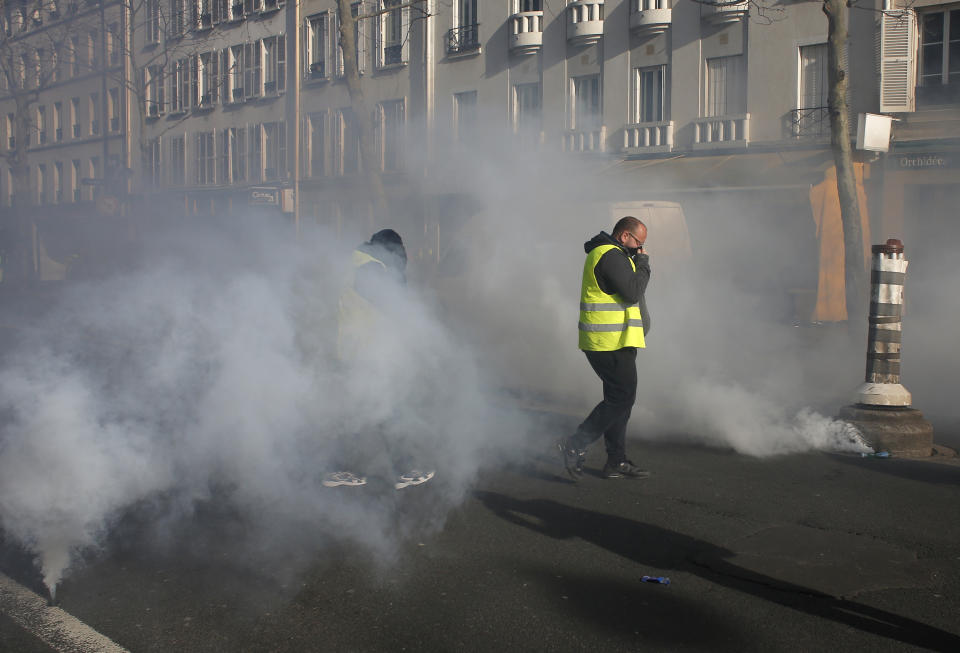 Yellow vest protesters walk through tear gas during a demonstration Saturday, Feb.16, 2019 in Paris. Yellow vest protesters are holding scattered demonstrations around Paris and the rest of France amid waning support for their movement. (AP Photo/Thibault Camus)