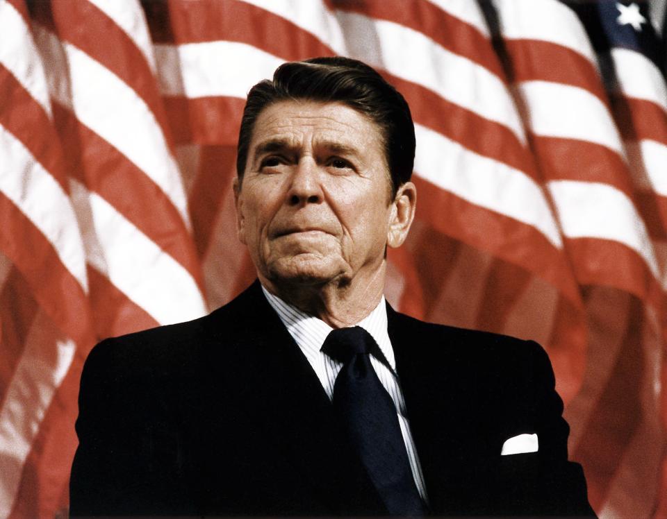 President Ronald Reagan stands tall against an American flag.